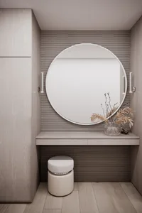 A minimalist vanity with a round mirror, wooden bench, and dried plants in a vase.
