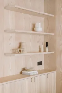 Modern wooden shelf with minimalist decor, including vases and candles.