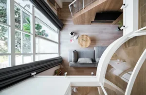 Modern living room with wooden flooring and furniture, featuring a round wooden table and grey sofa.