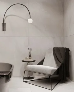 A modern, minimalist home interior featuring concrete walls, a metal-framed chair, and a curved light fixture.