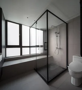 A minimalist modern bathroom with glass shower enclosure, white tiles, and a window seat.