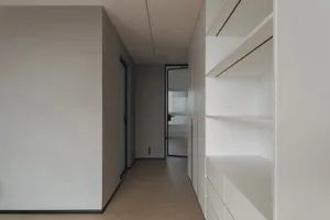 A minimalist entryway with neutral materials and a long, narrow corridor.