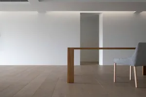A modern minimalist interior space featuring a wooden table with a single leg.