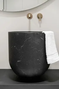A modern bathroom featuring a black marble sink with a white towel hanging on the side.