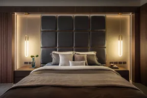 A modern bedroom featuring a black leather headboard, white bedding, and minimalist decor.