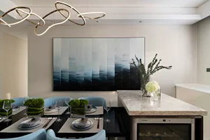 Modern dining room with marble table, glass chandelier, and abstract painting.