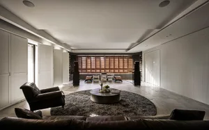 A modern living room with a circular rug, leather sofas, and concrete flooring.
