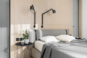 Contemporary bedroom with wood-paneled walls, a grey upholstered bed, and minimalist decor.