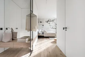 Modern minimalist bedroom featuring concrete walls and hardwood flooring with soft furnishings.