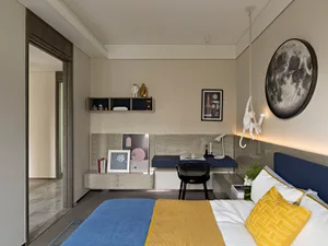 A modern minimalist bedroom featuring wooden furniture, including a bed with a blue and yellow blanket, a wall-mounted light 
