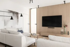Modern minimalist living room with white and grey furniture, a wooden wall, and a large flat-screen TV.