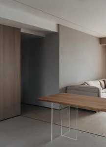 A minimalist living room with a wooden table and a glass wall.