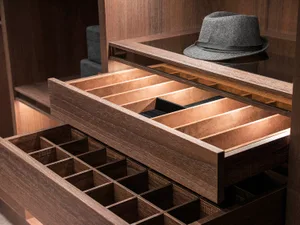 A meticulously organized closet with wooden drawers for hats and other accessories.
