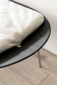 A minimalist black and white chair with leather upholstery and metal base.
