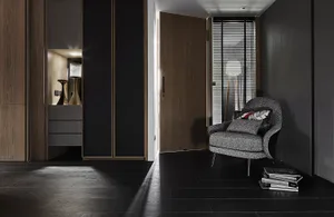 A modern industrial residential entrance with dark wood flooring and a gray upholstered chair.