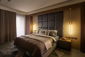 Modern bedroom featuring a fabric and leather upholstered bed against a contemporary wooden headboard and decorative pendant 