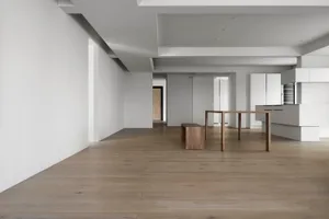 A modern minimalist kitchen featuring wooden furniture and white surfaces.