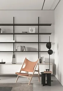 A minimalist living room with a sleek, modern lounge chair, a black floor lamp, and a white floating shelf.