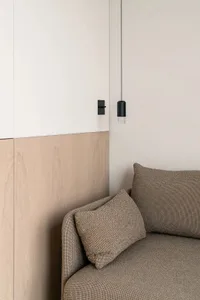 A cozy living room with a wooden accent wall and a grey sofa with brown cushions.