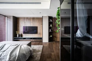 Spacious, minimalist bedroom featuring wood flooring and furniture.