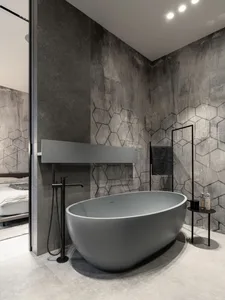 Modern bathroom featuring a sleek, concrete bathtub and geometric patterned wall.