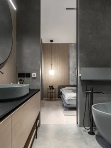 Modern bathroom with concrete walls and wooden finishes, featuring a freestanding bathtub and a floating vanity with a round 