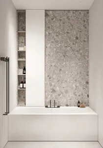 A modern bathroom designed with a terrazzo wall and a white bathtub.