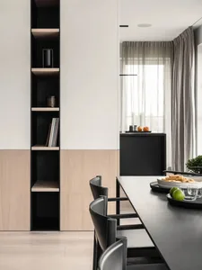 A modern dining room featuring minimalist furniture, sleek black and light wood finishes, and a long black dining table surro