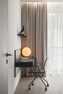 A modern home office with a wooden desk, leather chair, and globe lamp.