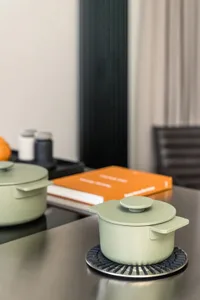 Modern kitchen with ceramic pots, book, and cooking utensils.