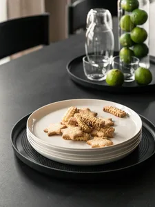 A modern kitchen scene featuring ceramic dishes with star-shaped cookies on a black round plate.