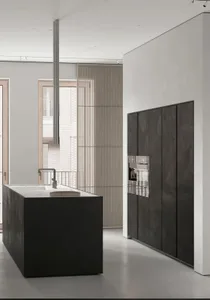 A modern kitchen with a large dark wood central island and concrete countertops.