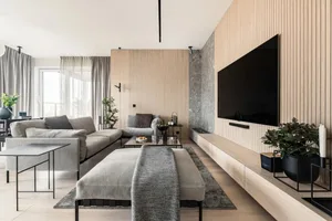 A modern living room featuring a wooden wall and grey furniture.