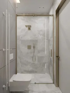 A modern bathroom with white marble tiles, a wall-mounted toilet, and a glass-enclosed shower.