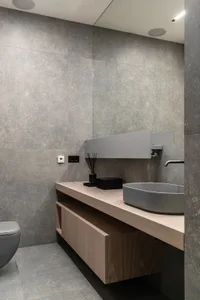 A modern minimalist bathroom featuring concrete tiles and a contemporary vanity with a wood finish.