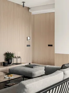Modern residential interior design featuring wood elements, a comfortable seating area, and a sleek glass table.