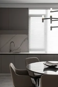 A modern kitchen with marble countertops and a dining area featuring a round table and chairs.