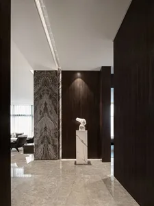 Modern entrance hall with marble flooring, walls, and art display.