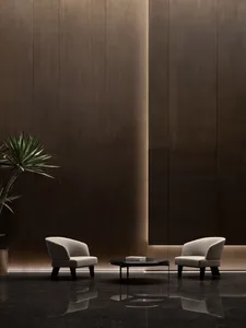Two minimalist armchairs and a desk in a modern lobby with wooden flooring and wall panels.