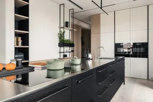 A contemporary kitchen with sleek black cabinetry and metallic finishes, featuring industrial-style lighting and a minimalist