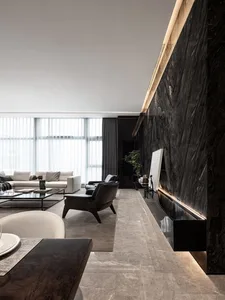 A modern living room featuring marble walls and furniture, with white sofas and black armchairs, large windows, and minimalis