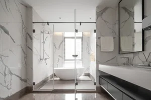 Modern bathroom with marble walls and floor, glass shower enclosure, freestanding bathtub, and floating vanity.