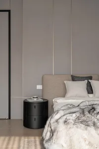 A modern bedroom featuring neutral-toned bedding, a wooden floor, and a minimalist design.