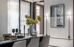 Modern dining room featuring a marble table, chairs, vase with greenery, and abstract art