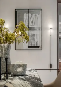 A modern abstract art piece mounted on a wall, surrounded by decorative vases with greenery and white berries.