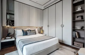A modern minimalist bedroom featuring a white bed with fabric and metal accents, surrounded by wooden furniture and a large w