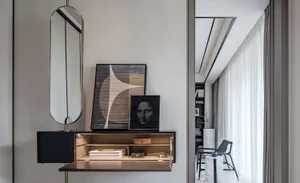 A modern living room with a desk featuring a sleek, black shelf and storage compartments, topped with abstract art pieces and