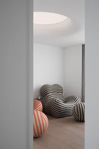 A minimalist living room with a unique, striped fabric chair in black and white stripes.