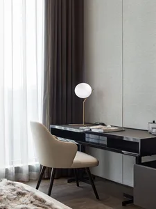 A minimalist office setup featuring a sleek desk with a modern lamp and a comfortable chair.