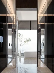 Modern bathroom featuring a spacious walk-in closet, glass shower enclosure, marble floor, and concrete wall accents, with a 